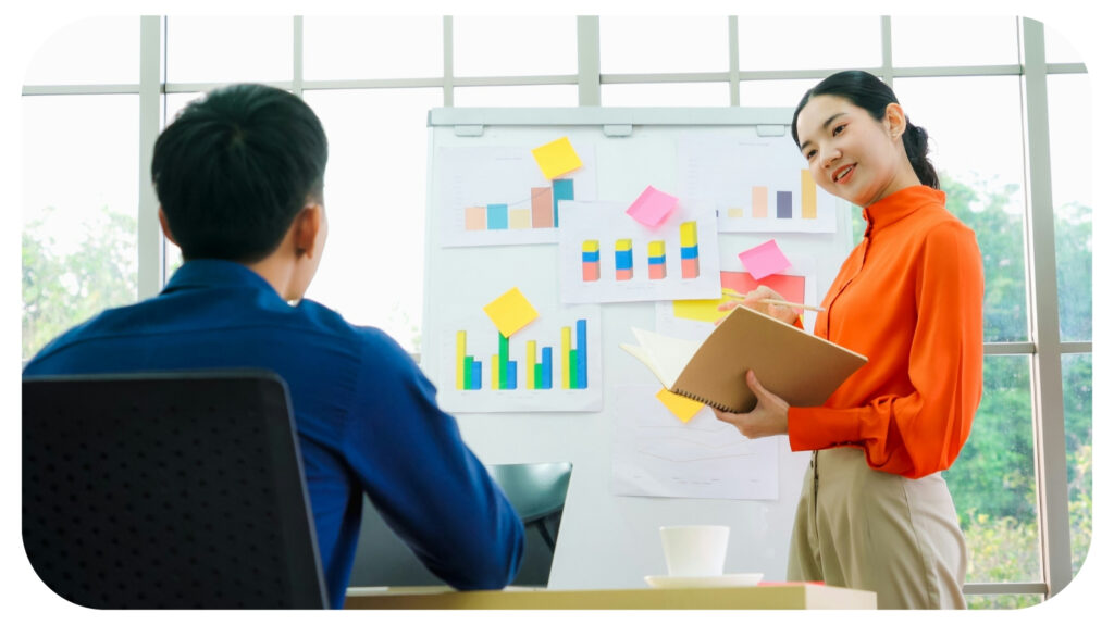 Young woman explains business data on white board.