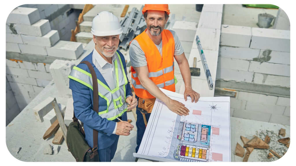 Top view of two smiling adult Caucasian men in safety helmets posing for the camera.