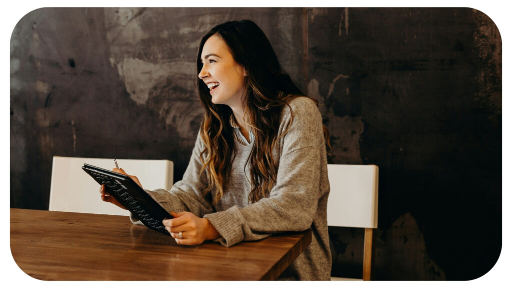 woman sitting around table holding tablet.