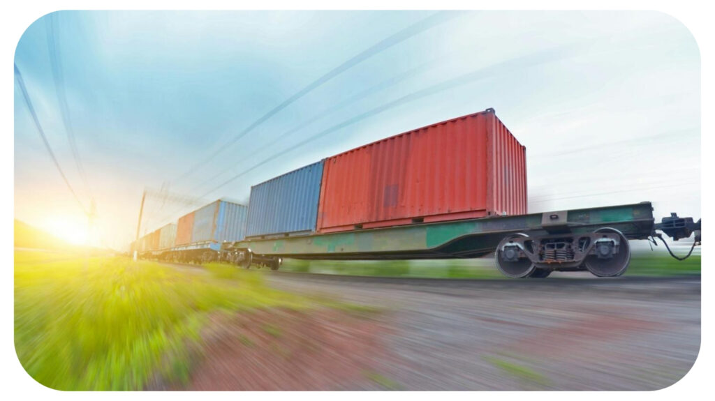 Freight train rides at speed with container and cargo at sunset.