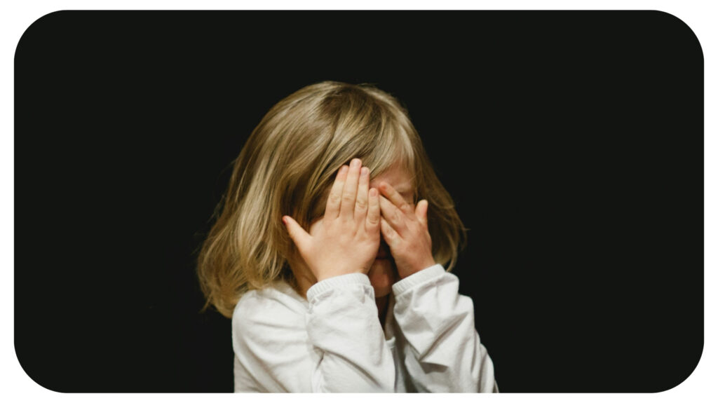 small girl covering her face with both hands.