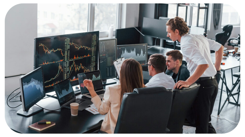 stock brokers discussing in modern office with many display screens.