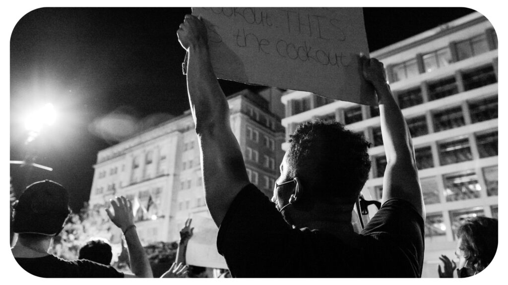 grayscale photo of man holding paper with hand.