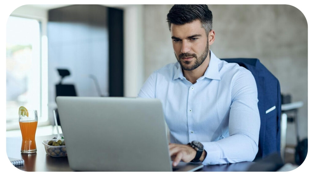 Young businessman working on laptop at his office desk.