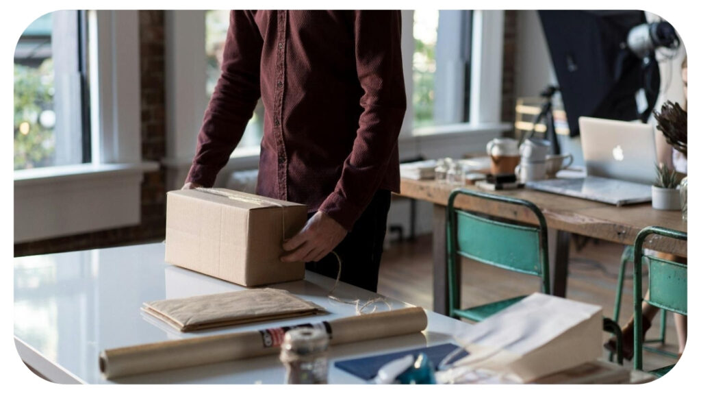 person holding cardboard box on table.