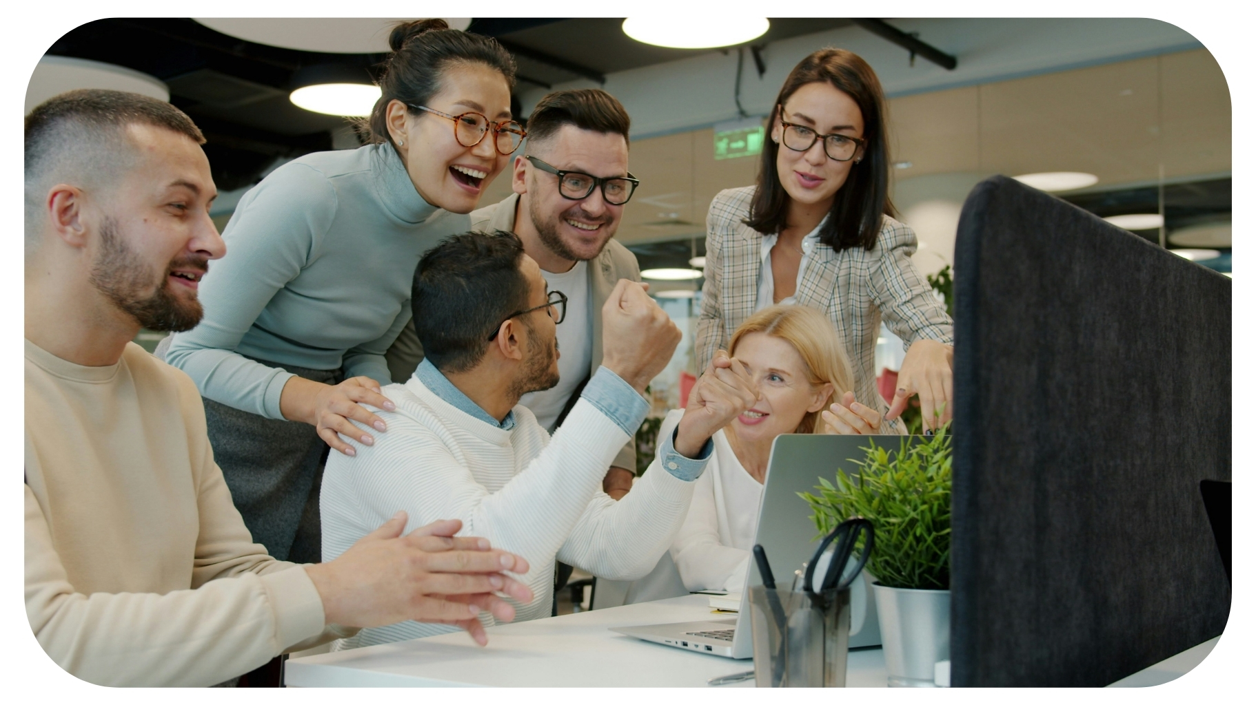 Diverse team celebrating success at office desk.