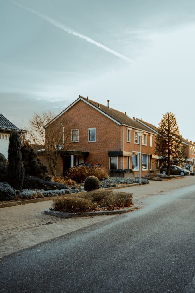 Brick two-story residential home exterior on a quiet street in early morning light.