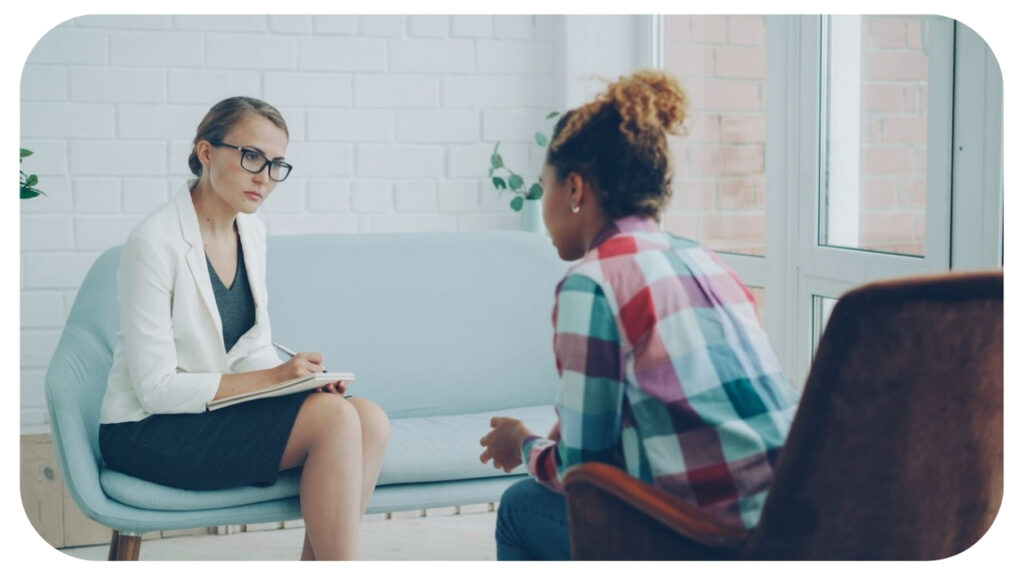 Woman talking with a family therapist taking notes during a counseling session in a bright office.