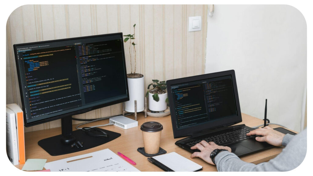 Developer working at a dual monitor setup with code editors open, writing and reviewing software.